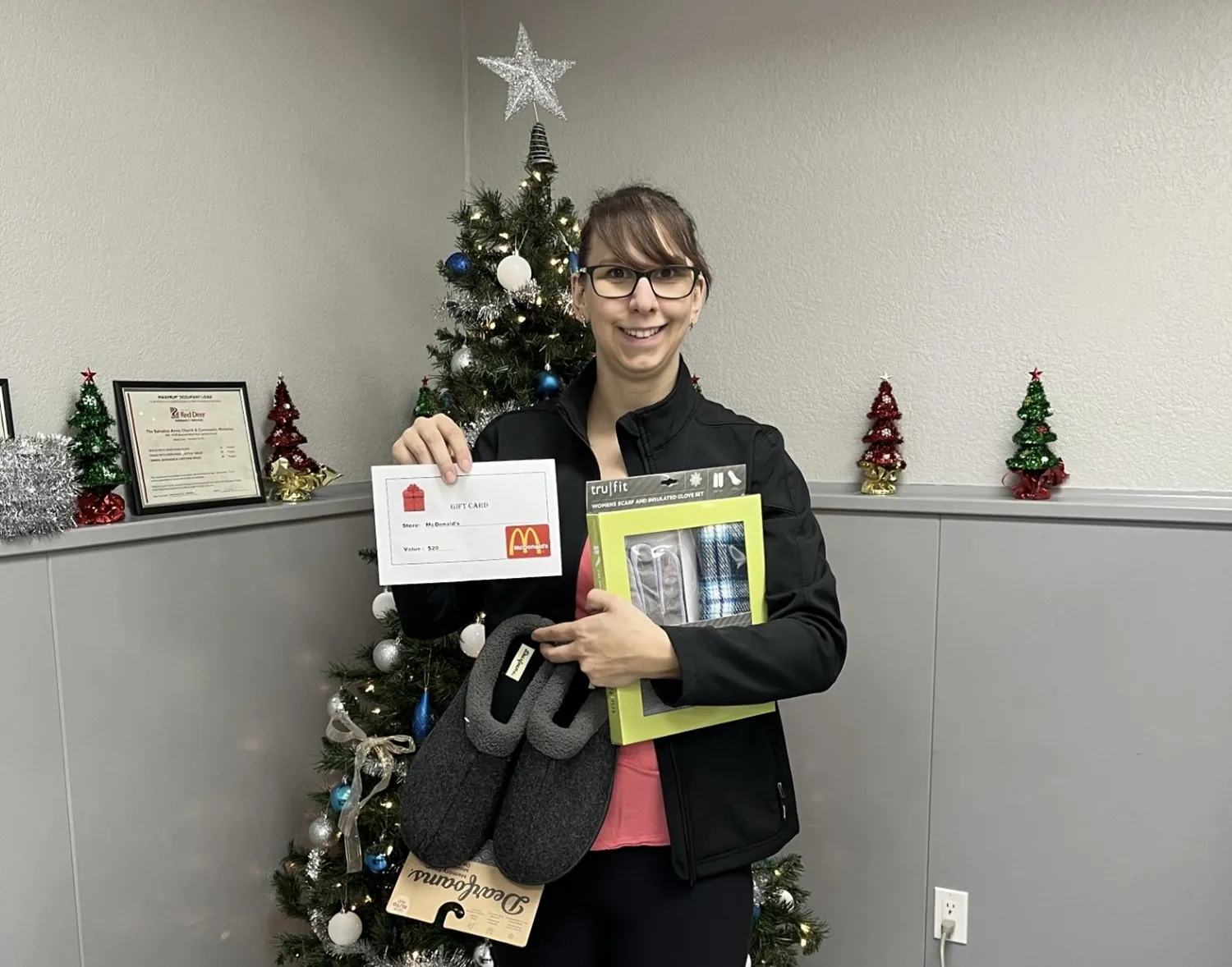 lady in front of christmas tree with gift card and present